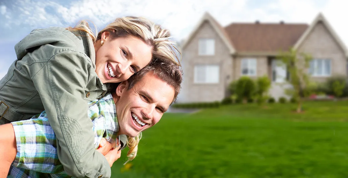 A smiling couple in front of a new home